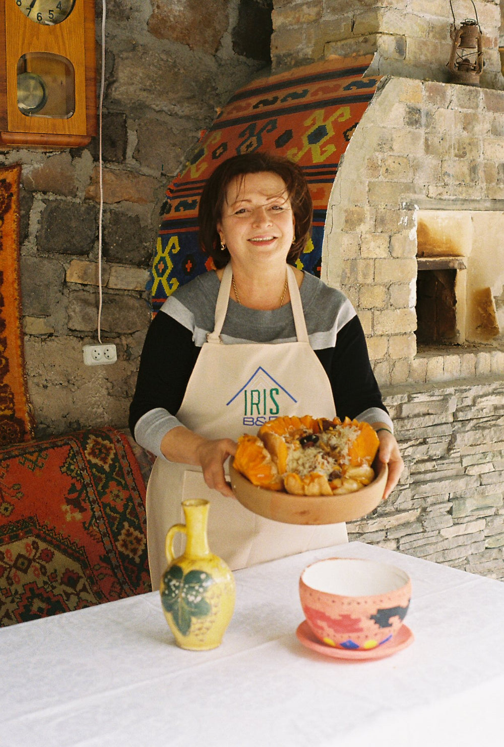 A woman holds a bowl of homemade pastries in her kitchen