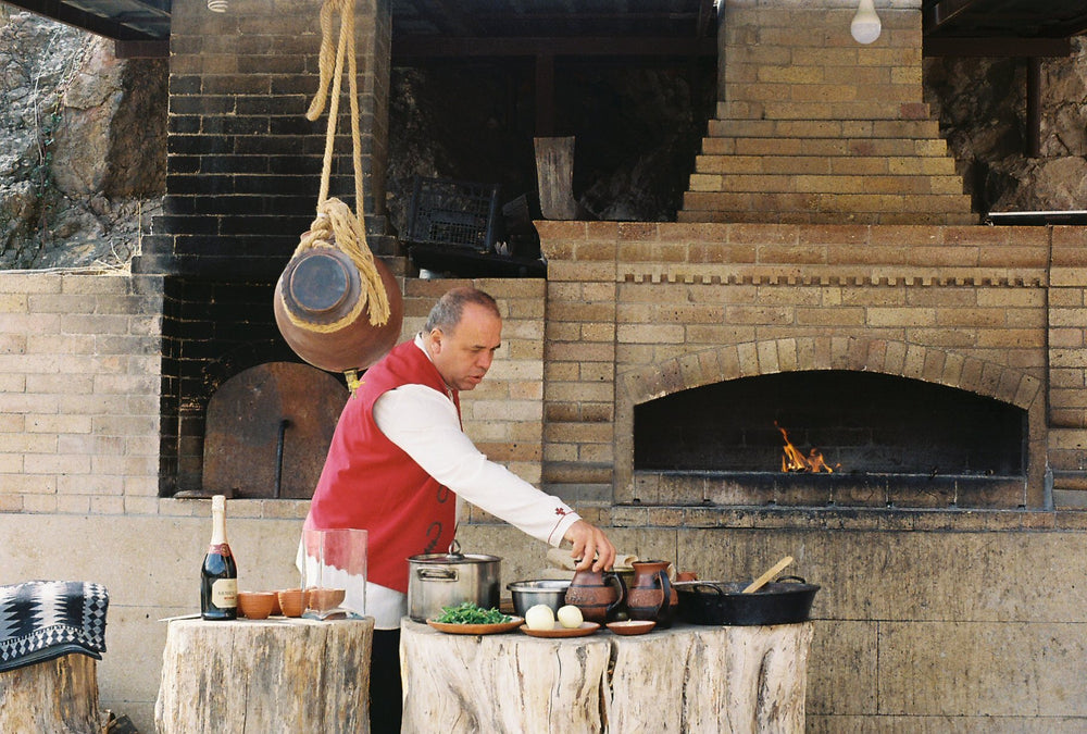A cook prepares food beside a wood-fired hearth