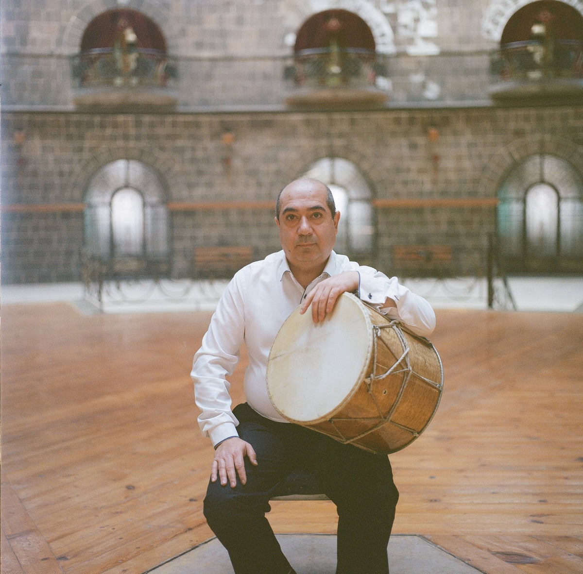 A musician seated with a dhol drum
