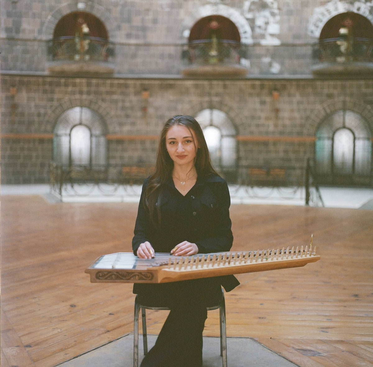 A musician seated with a qanun across her lap