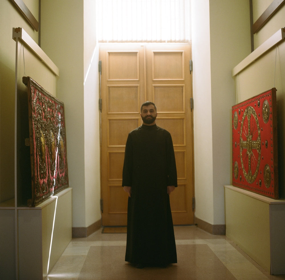 A priest of the Armenian Apostolic Church in a gallery hung with textiles